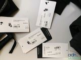 three white tags on a table with a black bag and a pair of gloves