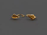 une paire de boucles d'oreilles en or posées sur une surface grise