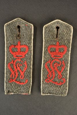 two british army rank badges, one with a crown and the other with a snake