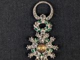 a close up of a diamond and emerald broocher on a black cloth
