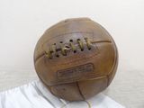 a brown leather soccer ball sitting on top of a white sheet