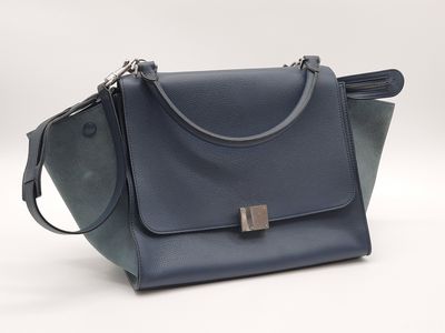 un sac à main bleu muni d'une poignée en métal sur fond blanc