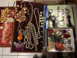 beaucoup de bijoux rangés dans une boîte posée par terre