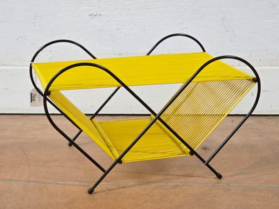 a yellow magazine rack sitting on top of a cement floor