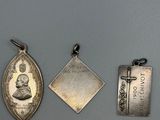 three silver pendants of various shapes and sizes on a gray surface