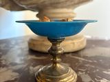 a blue glass bowl on a table with a statue in the background
