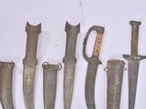 several old knives are lined up on a white surface