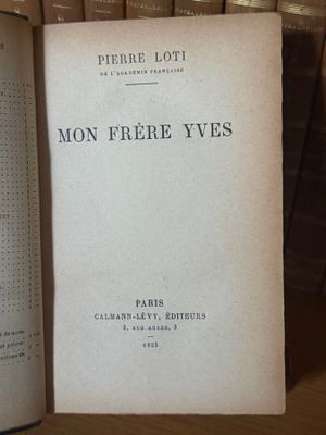 un livre posé sur une table, avec une pile de livres en arrière-plan