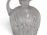 a clear glass pitcher with a handle on a white surface