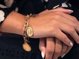 woman ' s hand with a gold bracelet and a gold coin bracelet