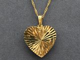 a gold heart shaped locke with a chain on a gray surface