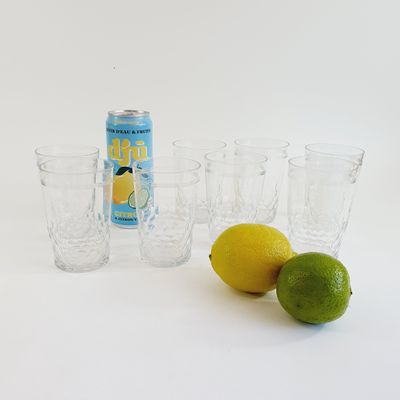 four glasses and a can of soda next to a lemon