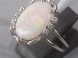an oplite and diamond ring sits on top of a black stone