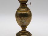 une lampe à huile ancienne en laiton posée sur un socle en bois, sur fond blanc