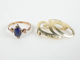 two gold rings and a lapel ring with a blue stone