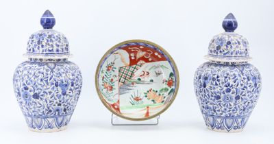 three blue and white vases and a plate on a stand