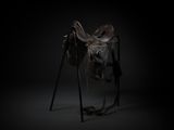 a horse saddle on a stand in a dark room