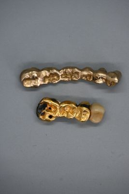 deux barrettes dorées et noires posées sur une surface blanche