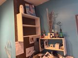 a room with a desk, shelves, and a picture on the wall