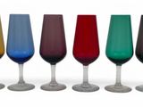 six verres à vin de couleurs différentes alignés sur une surface blanche