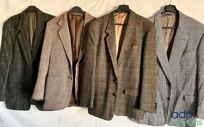 trois costumes sont suspendus à un cintre posé sur un lit