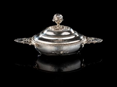 un plat à couvercle ancien en argent posé sur une surface noire avec un fond noir