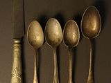 five spoons and a knife sitting on a table