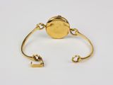 a close up of a gold cuff with a coin on it