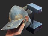sculpture of a hammer and a helmet on a stand on a black background