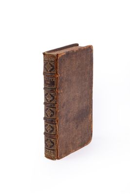 un vieux livre à la couverture brune posé sur une surface blanche