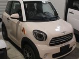 une petite voiture blanche garée dans un garage à côté d'une voiture blanche