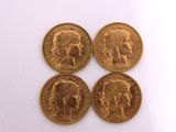 four gold sovereigns of different sizes and shapes on a white surface