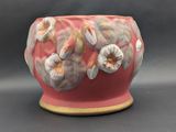 a red vase with flowers on it sitting on a table