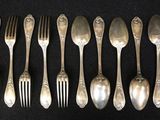six spoons and six forks are lined up on a black surface