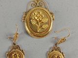 un gros plan sur un collier et des boucles d'oreilles en or, avec la photo d'une femme