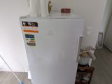 a white refrigerator in the corner of a room with a mop on the floor