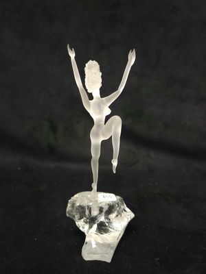 une sculpture blanche représentant une femme debout sur un rocher, les bras tendus