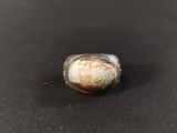 a close up of a ring with a stone in it on a black surface