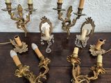 four antique brass wall sconces with candles on a wooden table