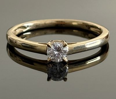 a close up of a diamond ring on a reflective surface