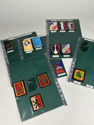 trois chemises vertes ornées de différents types d'insignes, posées sur une table