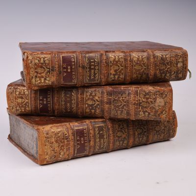 trois vieux livres empilés sur une surface blanche