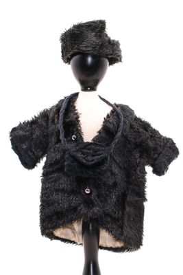 un mannequin vêtu d'un manteau noir et coiffé d'un chapeau