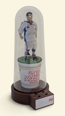 statue d'un footballeur placée dans une coupe sous un dôme de verre