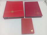 Trois livres rouges sont posés les uns à côté des autres sur une table.