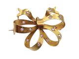 an image of a gold bow brooch with pearls on it