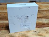 Des AirPods d'Apple sont posés sur une table en bois