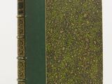a green book sitting on top of a white table next to a white wall