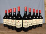 six bottles of red wine are lined up on a wooden table