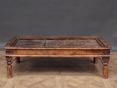 an old wooden coffee table with a glass top on a parquet floor